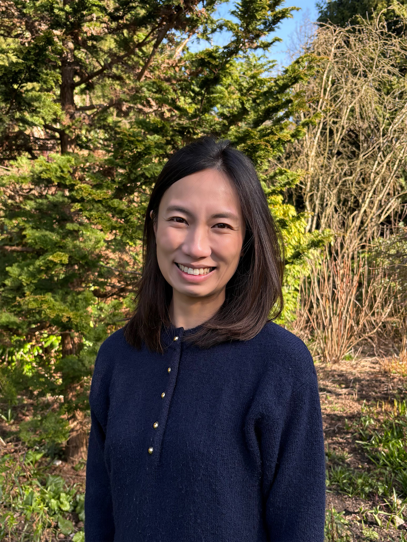 Wendy Tse smiles in front of a field of greenery.